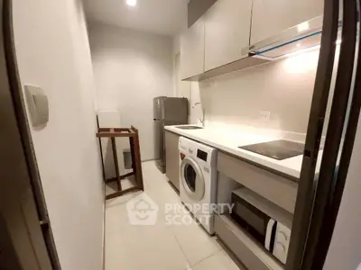 Modern kitchen with sleek appliances and compact design, featuring washing machine and microwave.