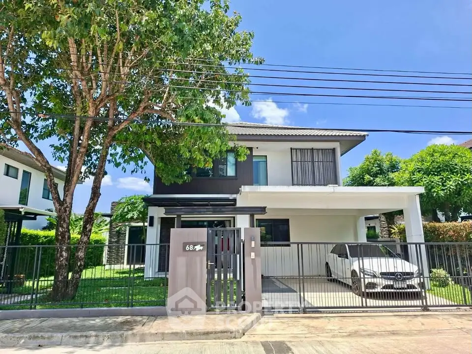 Modern two-story house with carport and lush greenery in a serene neighborhood.