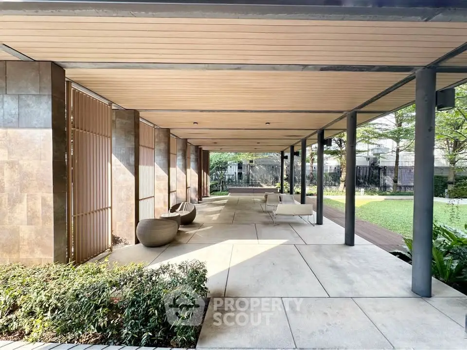 Elegant outdoor common area with modern seating and lush greenery in a luxury residential complex.