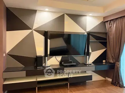 Modern living room with stylish geometric wall design and sleek entertainment center.