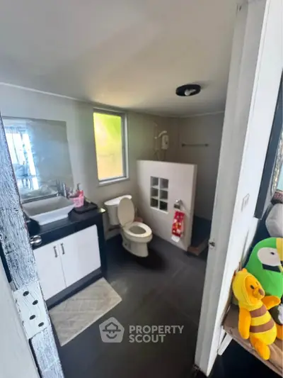 Modern bathroom with sleek fixtures and natural light, featuring a stylish vanity and toilet.
