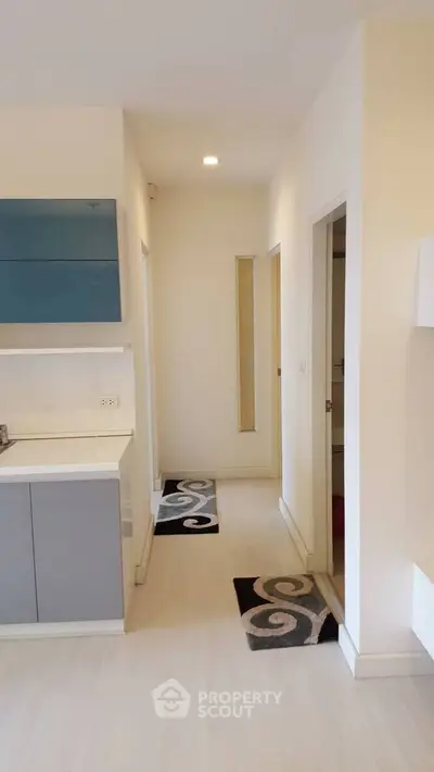 Modern apartment hallway with sleek cabinetry and stylish rugs, showcasing minimalist design.