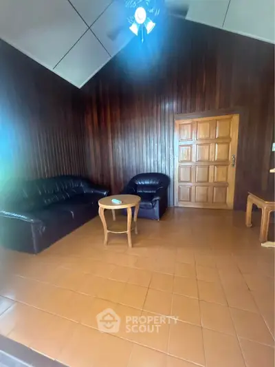 Cozy living room with wooden walls and leather furniture, perfect for relaxation.