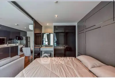 Modern studio apartment with sleek kitchen and cozy bedroom area, featuring a washing machine and stylish decor.