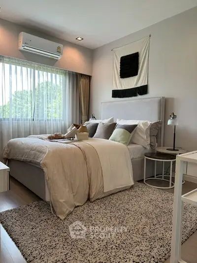 Modern bedroom with cozy decor and large window for natural light.