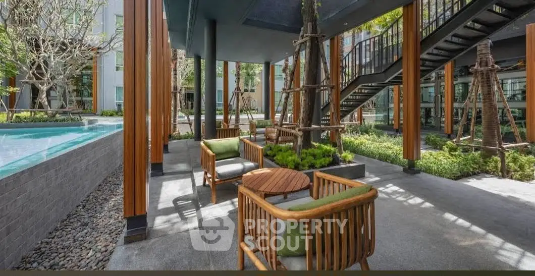Modern outdoor seating area with pool and garden in luxury apartment complex.