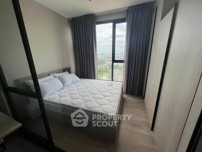 Modern bedroom with large window offering stunning city view, featuring cozy bed and elegant decor.