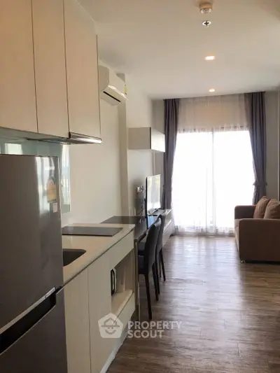 Modern open-layout living room with kitchen, featuring sleek appliances and natural light.