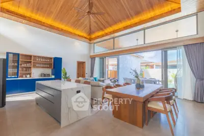 Luxurious open-plan living room with modern kitchen and dining area, featuring high wooden ceilings and natural light.