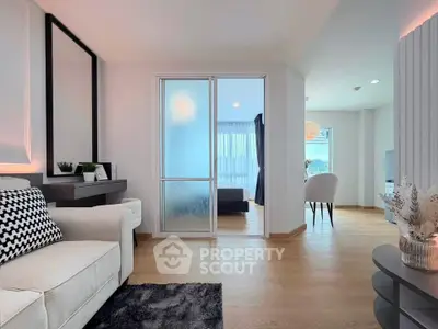 Modern living room with elegant decor and sliding door leading to a bright bedroom.