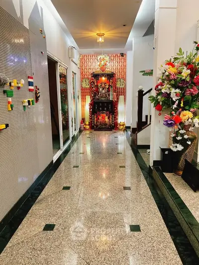 Elegant hallway with polished floors and vibrant floral decor leading to a traditional altar.