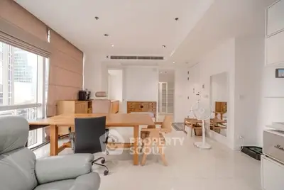 Spacious modern living room with sleek furniture and large windows in a high-rise apartment.