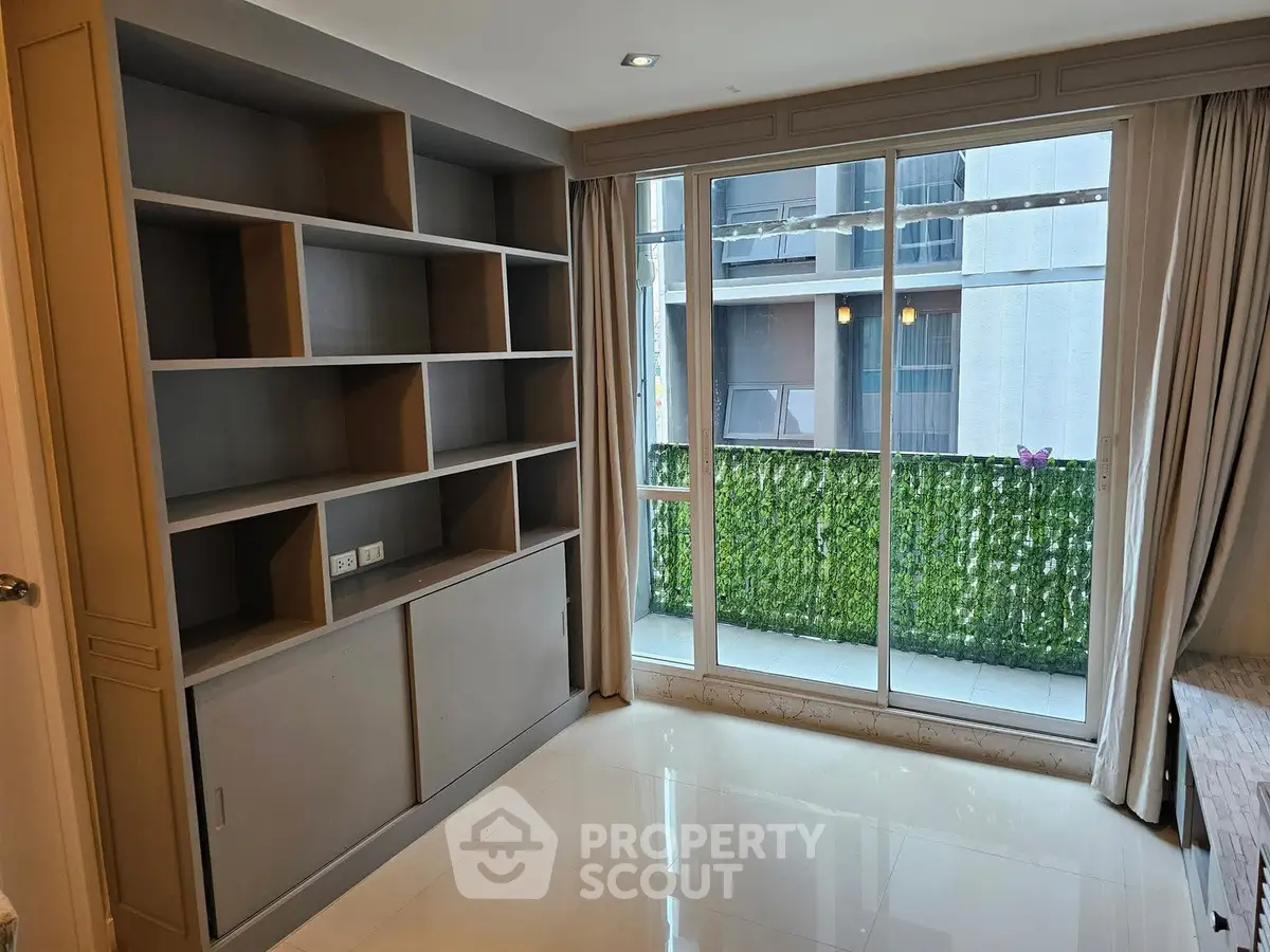 Spacious room with built-in shelving and large window overlooking greenery, perfect for modern living.