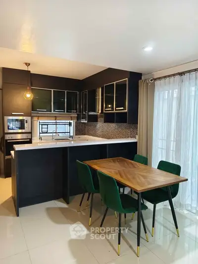 Modern kitchen with sleek black cabinets and stylish dining area with green chairs.