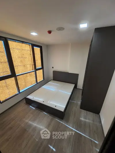 Modern bedroom with large windows and sleek flooring, perfect for urban living.