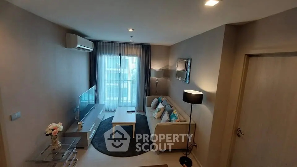 Modern living room with stylish decor and natural light, featuring a cozy sofa and flat-screen TV.