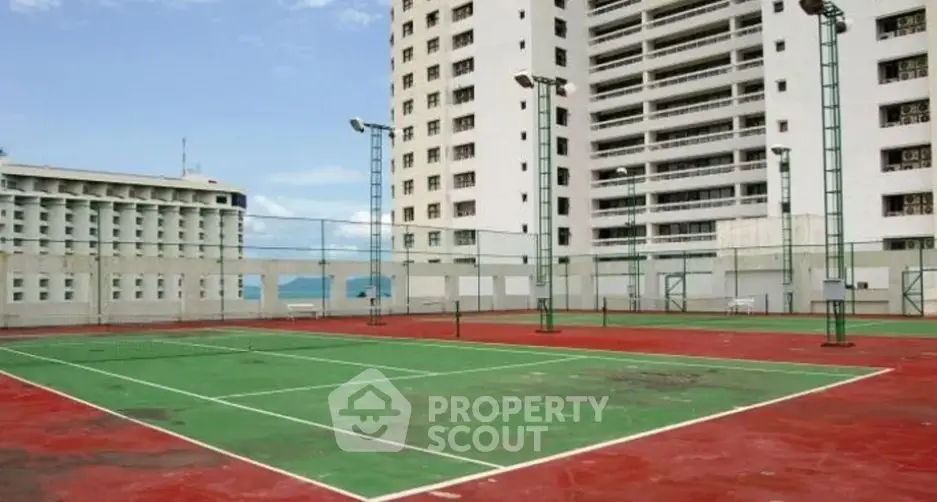 Spacious tennis court with high-rise building backdrop in urban setting.