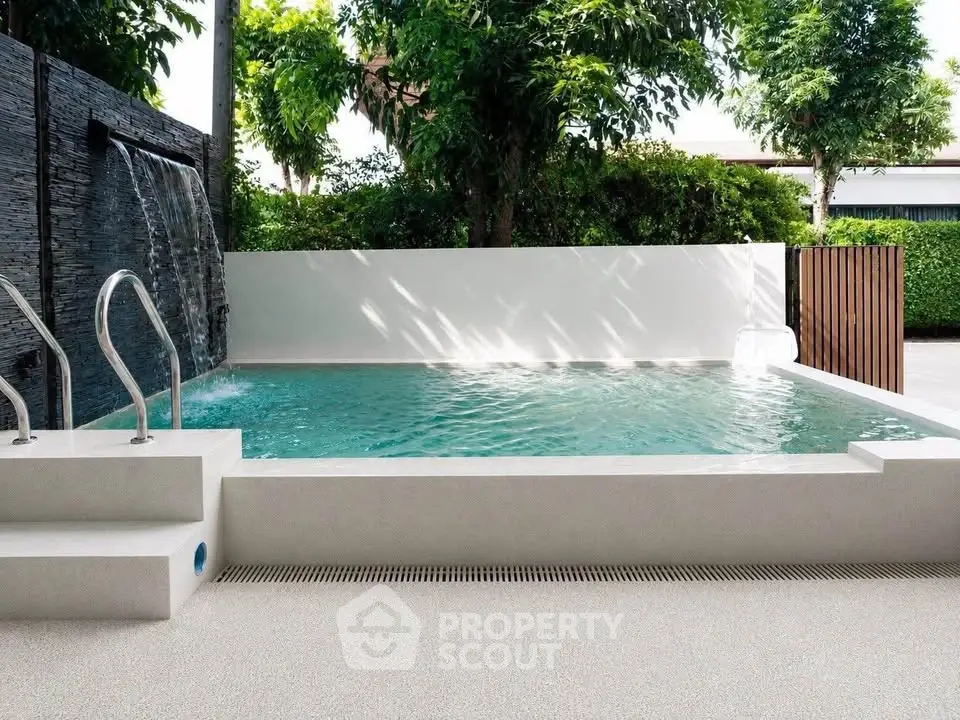 Luxurious private pool with waterfall feature in serene garden setting.