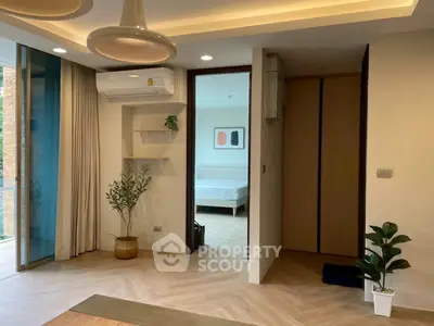 Modern living room with stylish decor and view into a cozy bedroom