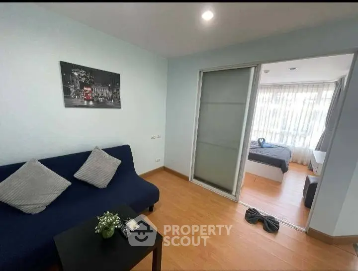 Modern apartment with cozy living room and sliding door to bedroom, featuring stylish decor and natural light.
