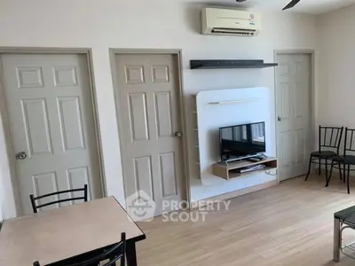Modern living room with air conditioning and TV setup, featuring minimalist furniture and wooden flooring.