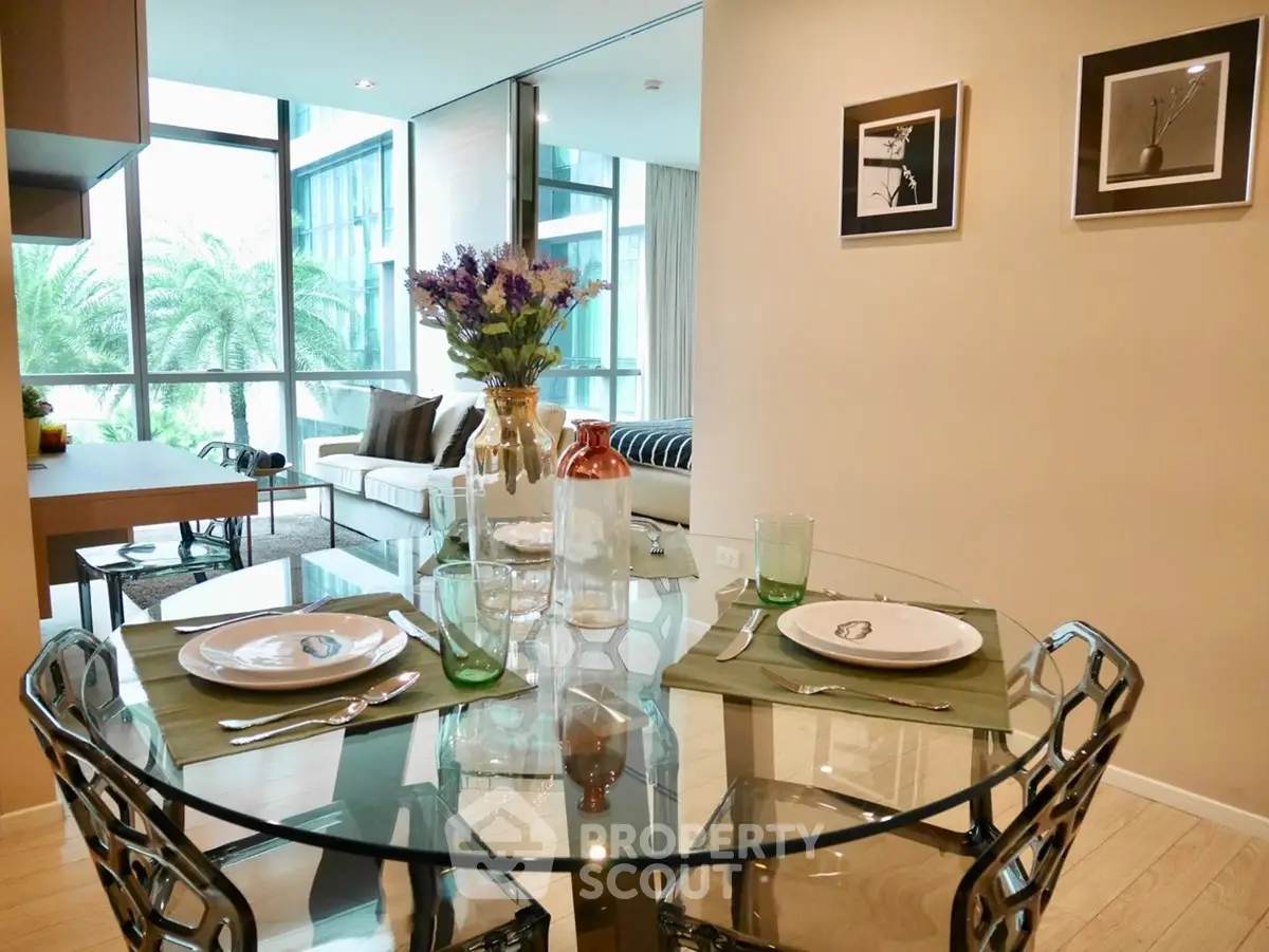 Modern dining area with glass table and stylish decor in a bright apartment with large windows.