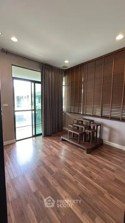 Spacious living room with wooden flooring and large windows for natural light.
