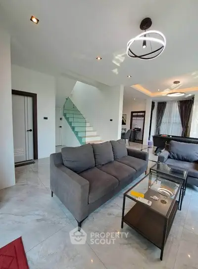 Modern living room with stylish furniture and elegant staircase in open layout