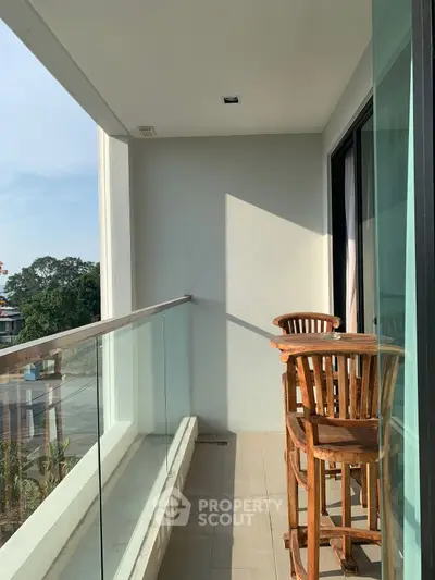 Charming balcony with wooden seating and glass railing, perfect for enjoying serene views.