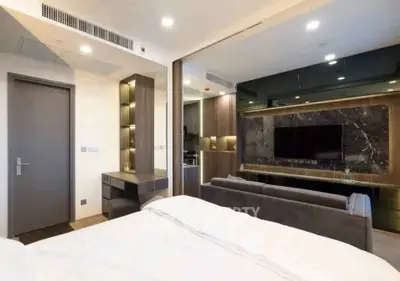 Modern bedroom with open layout to living area, featuring sleek design and contemporary furnishings.
