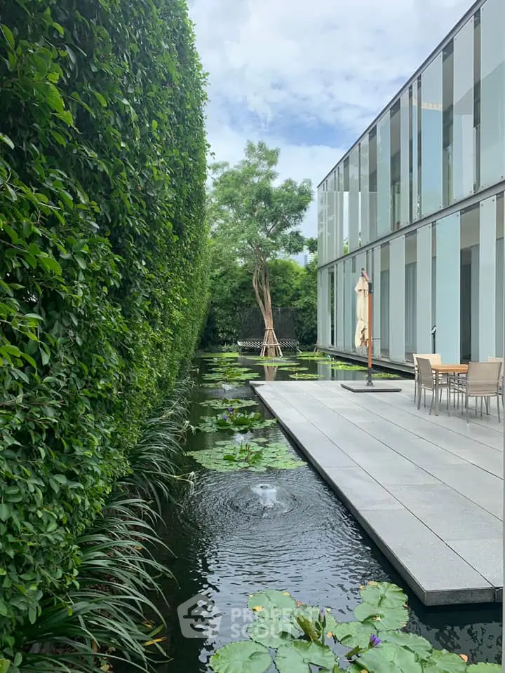 Modern architectural exterior with serene water feature and lush greenery.