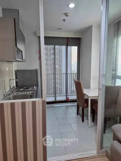 Modern kitchen with open layout and dining area leading to a balcony with city view.