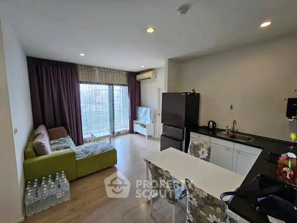Modern open-plan living room and kitchen with large window and stylish decor.