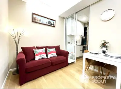 Cozy and inviting living room with a plush red sofa, sleek dining area, and warm wooden flooring, perfect for modern living.