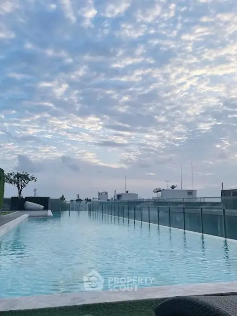 Stunning rooftop pool with panoramic city views and serene sky backdrop.