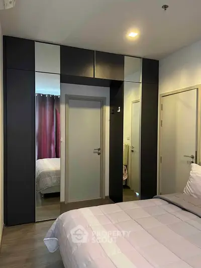Modern bedroom with mirrored wardrobe and cozy bedding in stylish apartment.