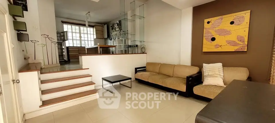 Spacious living room with modern decor and elevated kitchen area, perfect for entertaining.