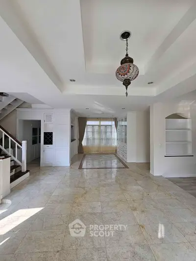 Spacious open-plan living area with elegant chandelier and marble flooring