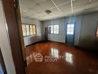 Spacious empty room with wooden flooring and natural light, ideal for customization.