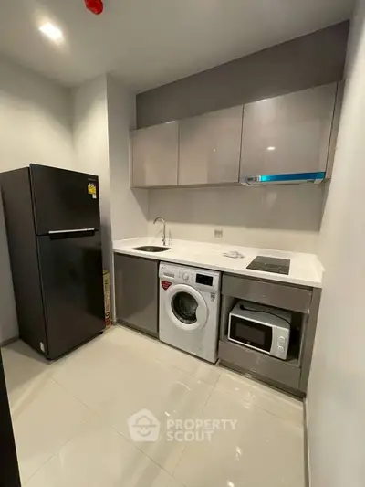 Modern compact kitchen with appliances including fridge, washing machine, and microwave.