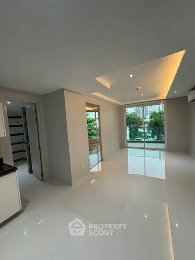 Spacious modern living room with glossy floors and large windows offering garden views.