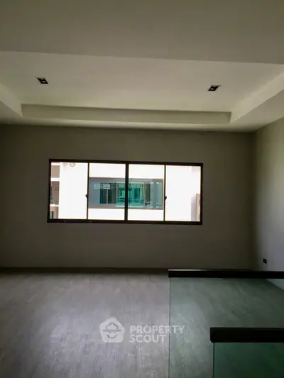 Spacious modern living room with large window and sleek flooring in a contemporary apartment.