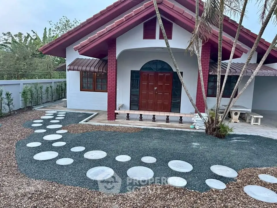 Charming single-story house with unique circular stone pathway and lush greenery, perfect for serene living.