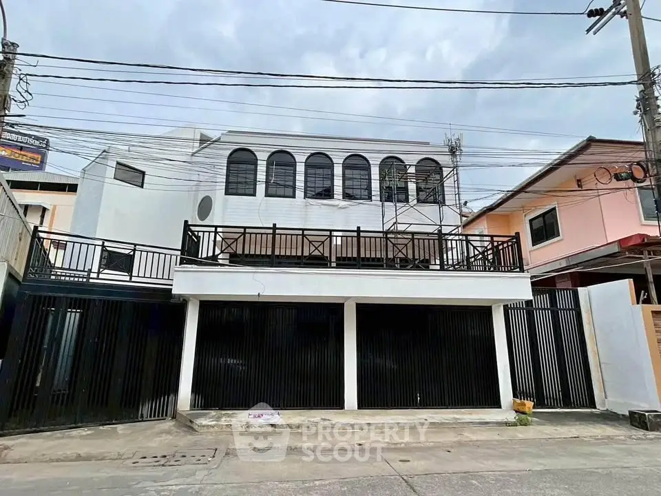 Modern two-story building with sleek black and white exterior design, featuring large arched windows and gated entrance.