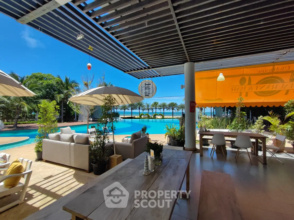 Luxurious outdoor pool area with stylish seating and dining, surrounded by lush greenery and ocean views.