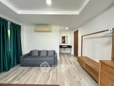 Spacious living room with modern decor and air conditioning, featuring a sleek sofa and elegant wooden furniture.