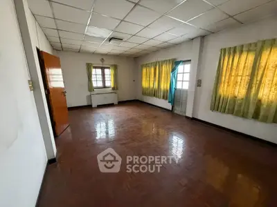 Spacious empty room with wooden flooring and large windows, ideal for customization.