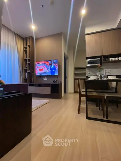 Modern living room with open kitchen, sleek wooden furniture, and ambient lighting.