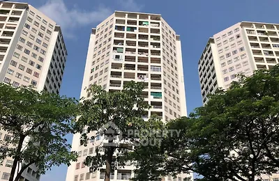 Modern high-rise residential buildings with lush greenery and clear blue sky.