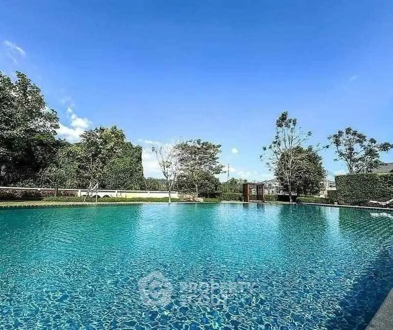 Luxurious outdoor pool with clear blue water and lush greenery, perfect for relaxation.